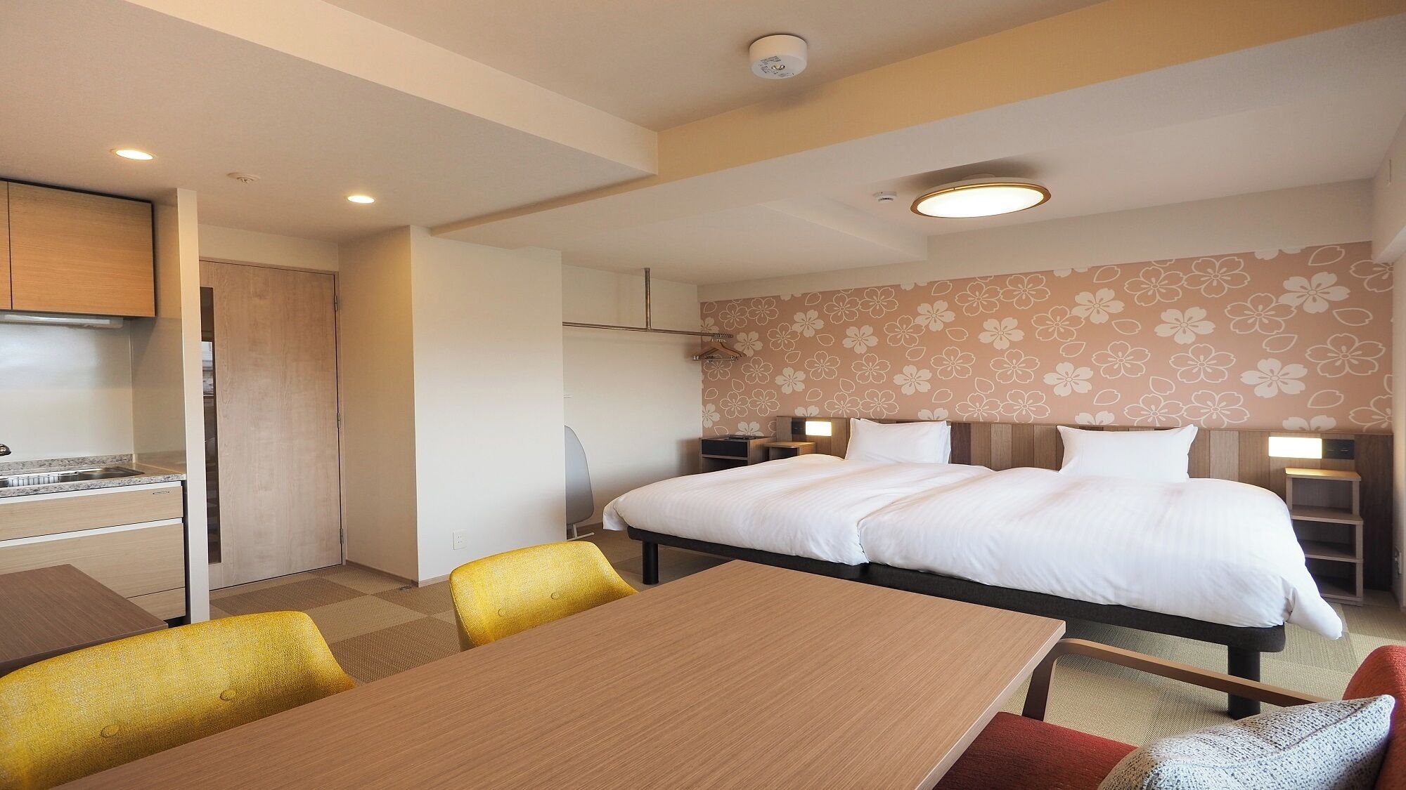 A hotel room with a bed, bedside tables, a desk, and a chair.
