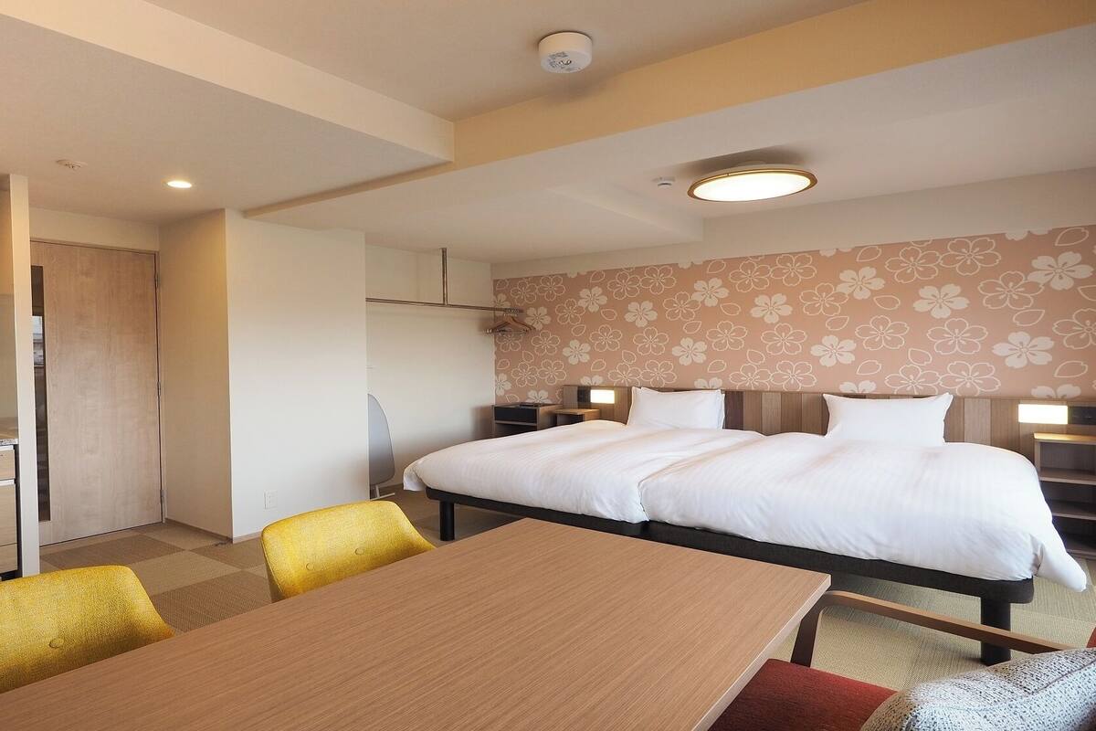 A hotel room with a bed, bedside tables, a desk, and a chair.
