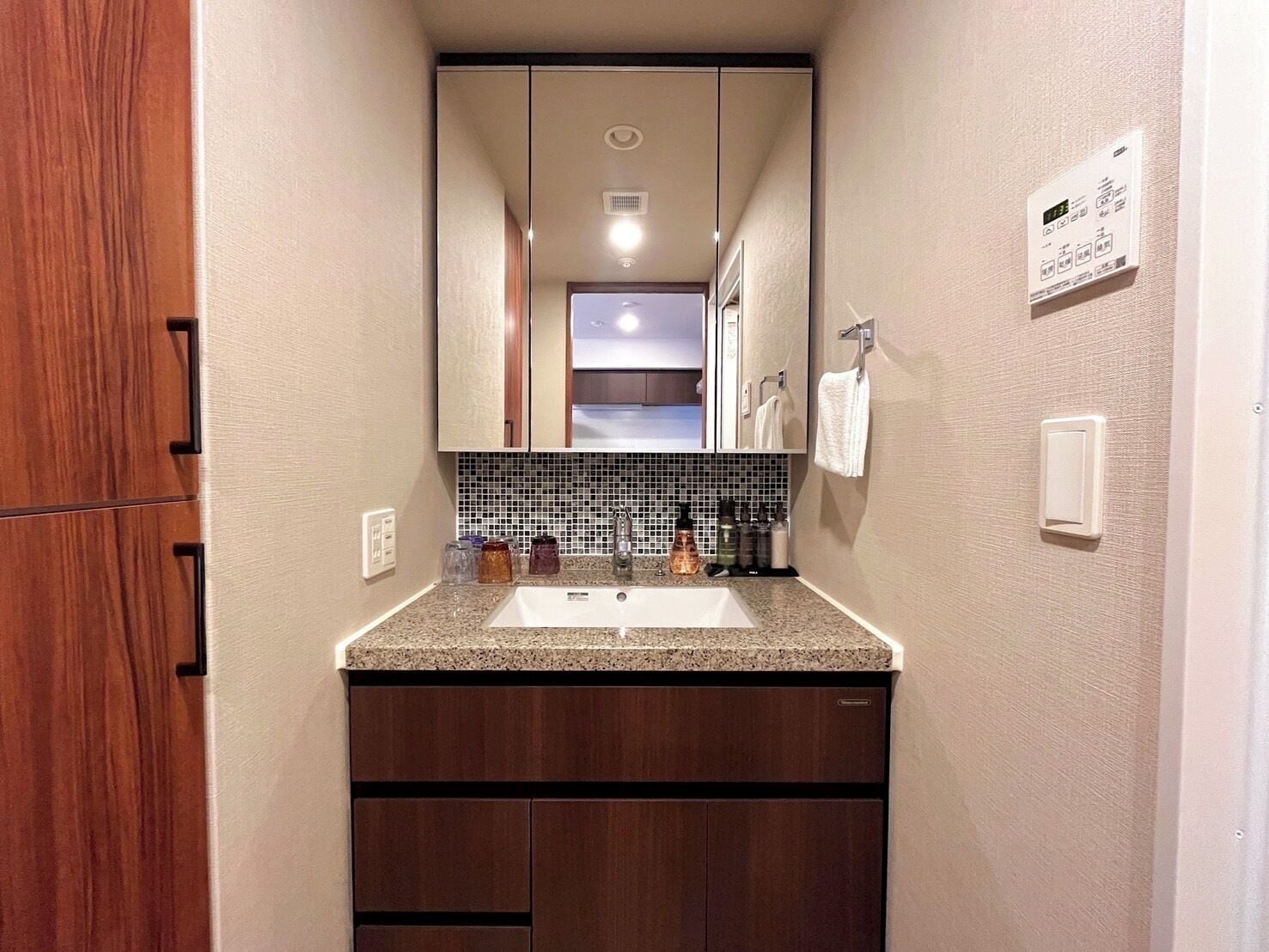 A compact bathroom with a granite countertop, a sink, a mirror, and a tiled backsplash.
