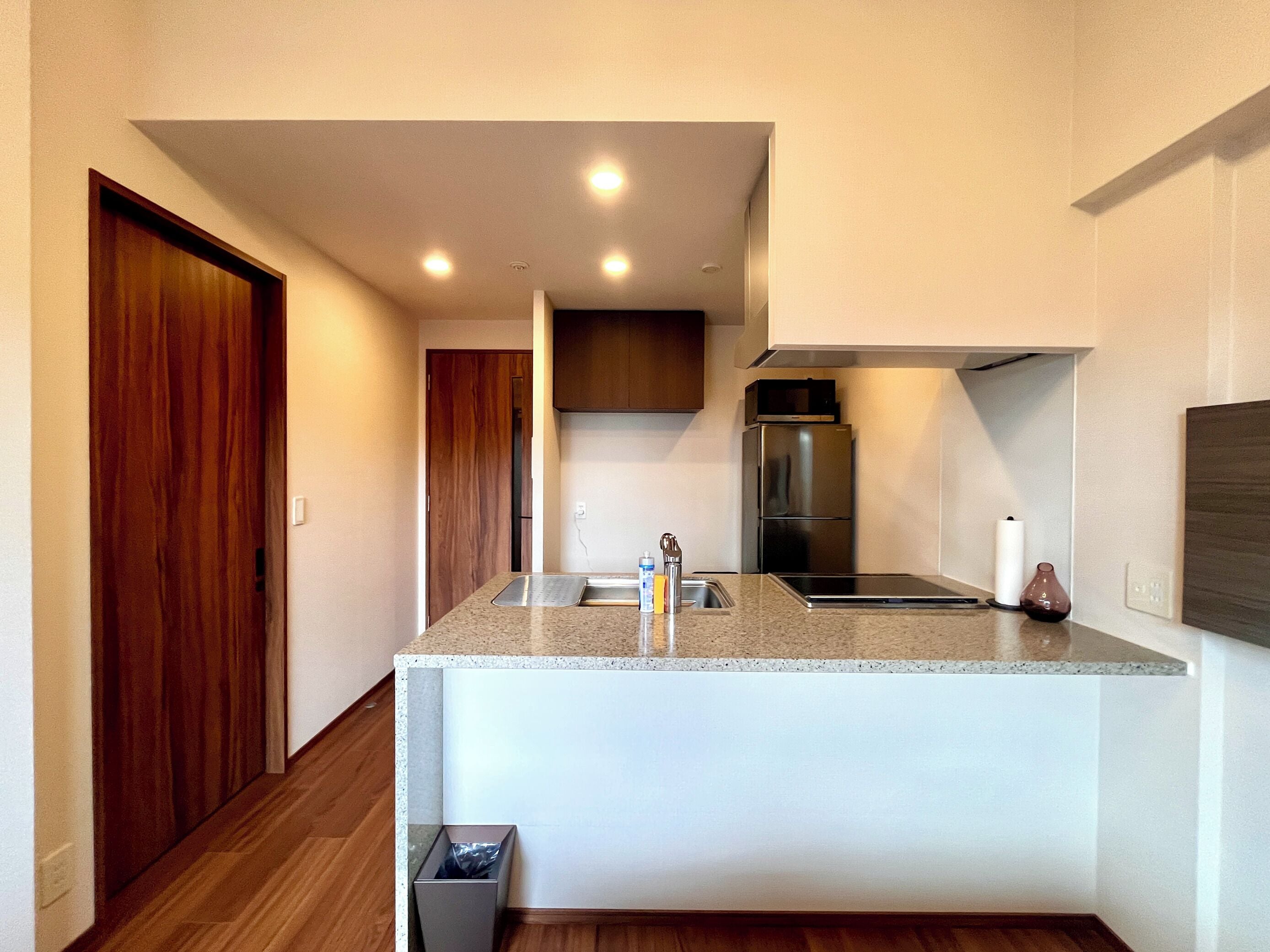 A modern kitchen with a granite countertop, stainless steel appliances, and wooden flooring.
