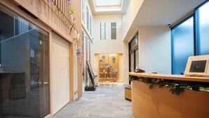 A hotel lobby with a curved reception desk, a staircase, and a seating area. - Hiyori Residence Kyoto Kamogawa (Kyoto)
