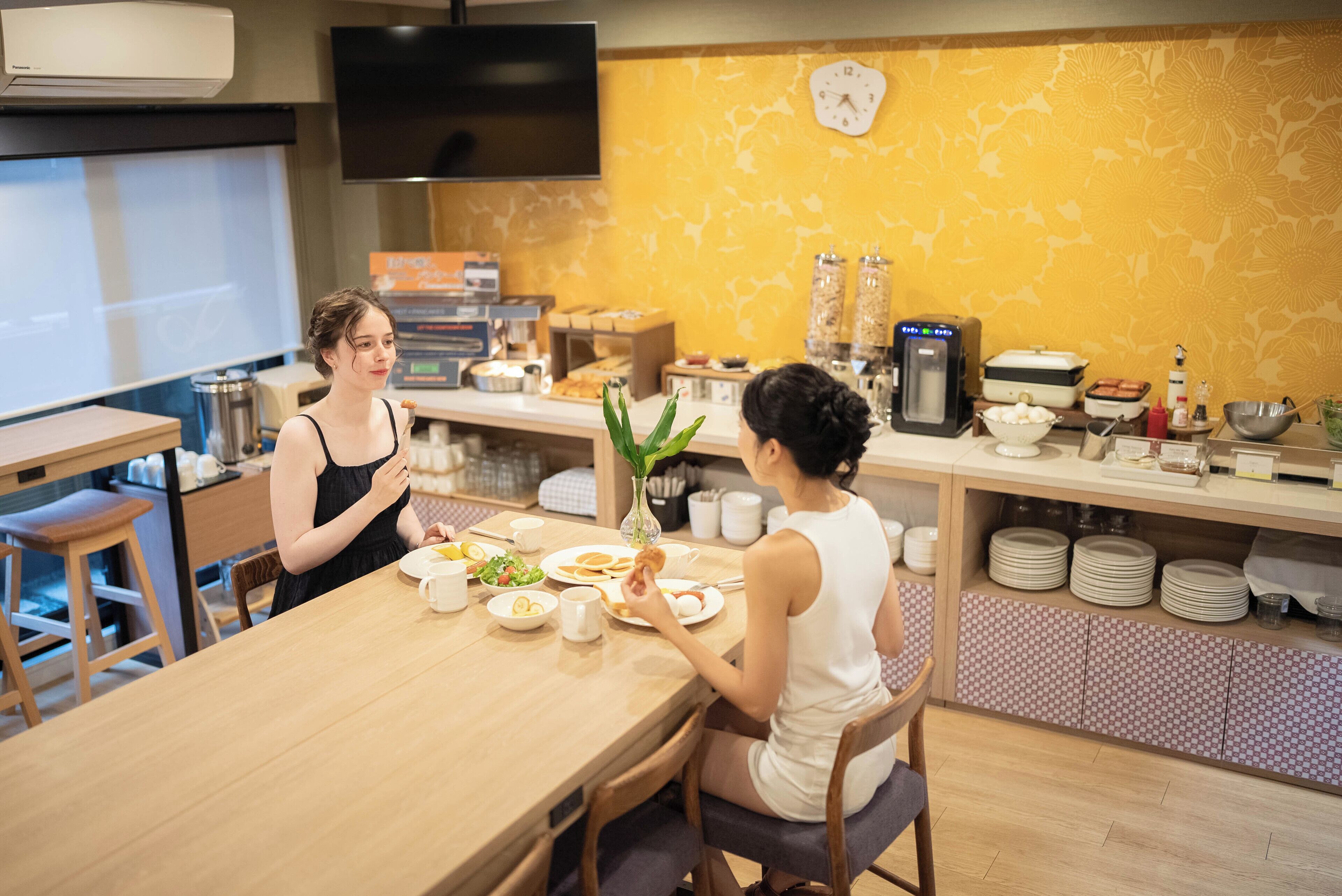A dining area with a wooden table, chairs, and a buffet setup with various food items and condiments.