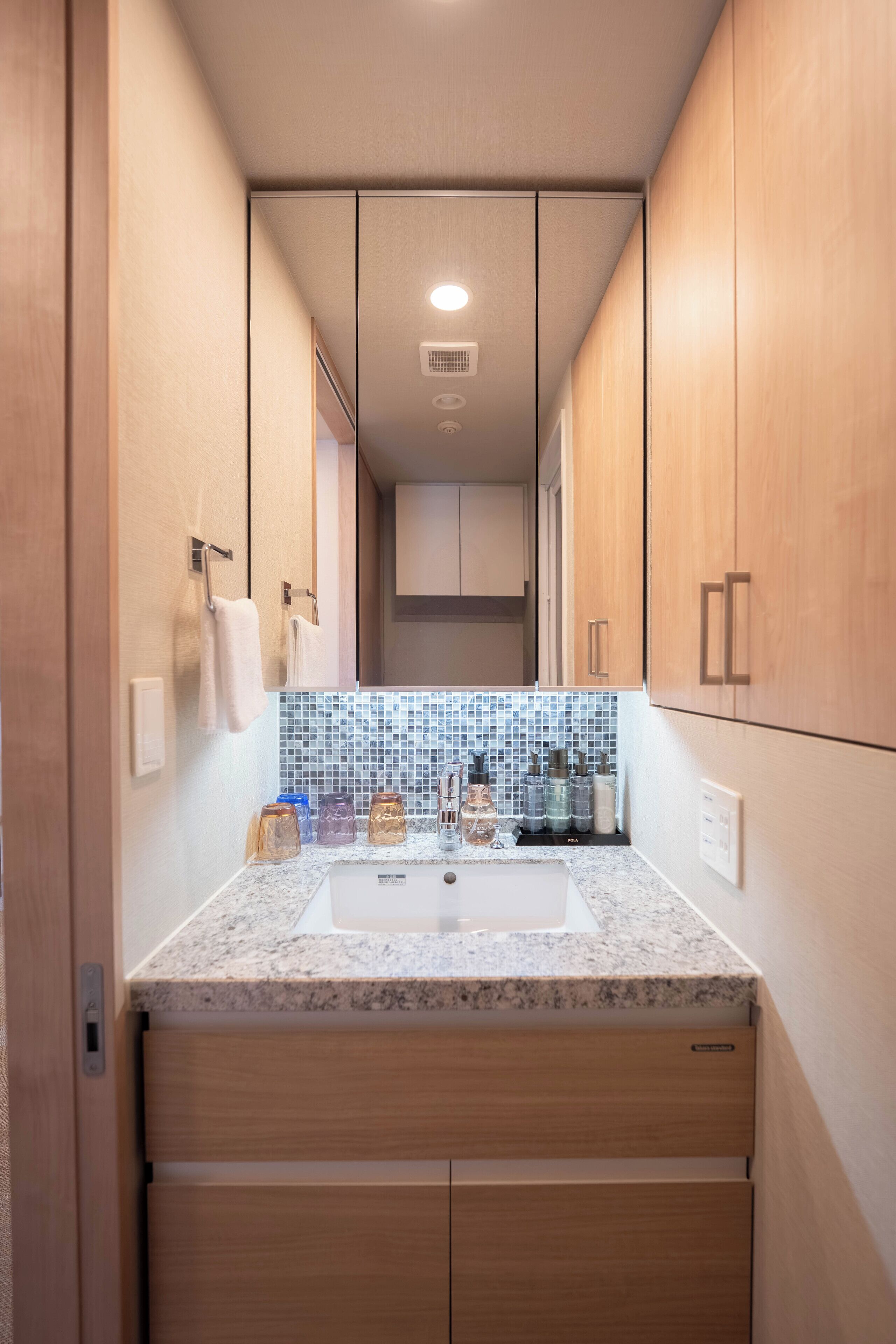 Une petite salle de bain avec des meubles en bois, un pare-feu en carreaux et un comptoir en granit.