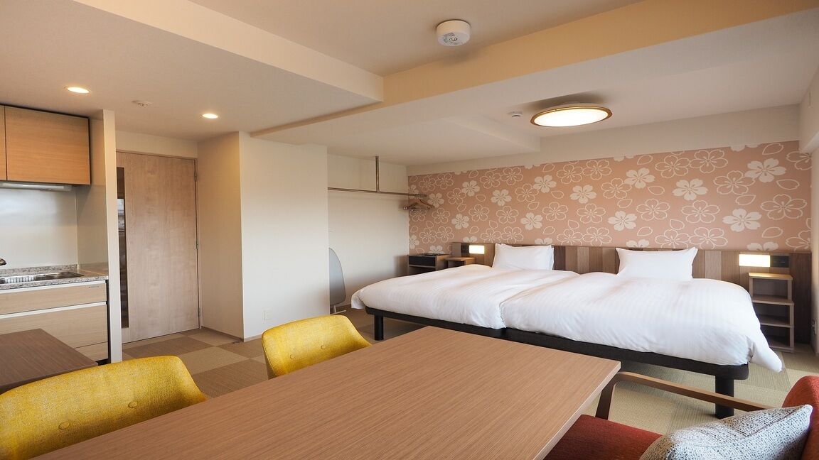 Hotellihuone, jossa on sänky, yöpöydät, työpöytä ja tuoli.