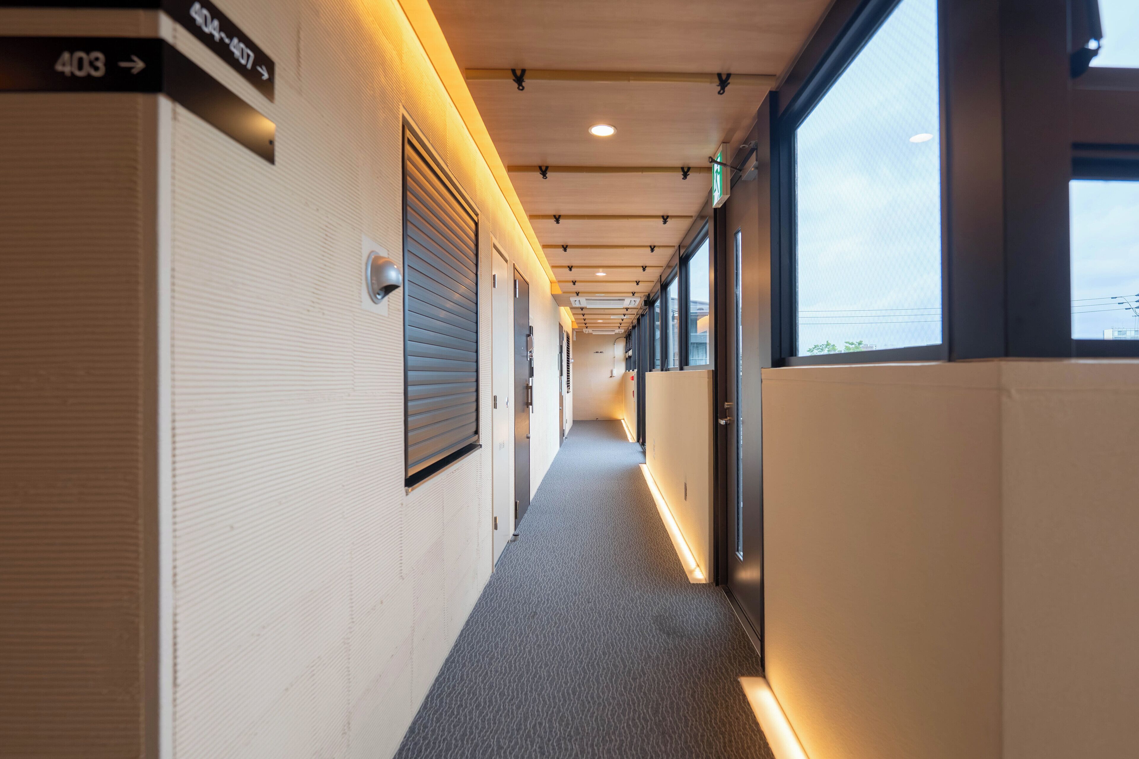A corridor with directional signs, a carpeted floor, and large windows.