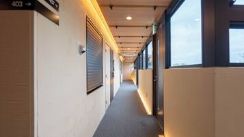 A corridor with directional signs, a carpeted floor, and large windows.