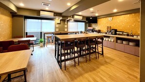 A modern restaurant with a long wooden table and chairs, a kitchen area, and a clock on the wall. - Hiyori Residence Kyoto Kamogawa (Kyoto)