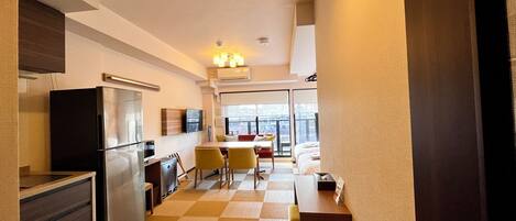 Habitación de hotel moderna con cocina, una mesa de comedor y un amplio ventanal con vistas a la ciudad.