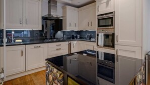 A modern kitchen with white cabinetry, a black countertop, and stainless steel appliances including a refrigerator, oven, and microwave. - Gorgeous 2BD Flat With Patio - South Kensington! (London)