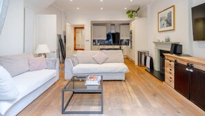 A modern living room with a sofa, coffee table, and a fireplace. - Gorgeous 2BD Flat With Patio - South Kensington! (London)