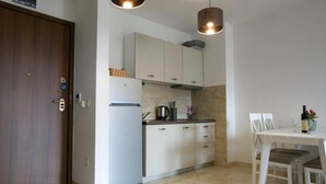 Een moderne keuken met witte kasten, een inbouwoven en een eethoek met een tafel en stoelen.