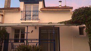 Ein zweistöckiges Haus mit Balkon, Schornstein und einem kleinen Fenster.