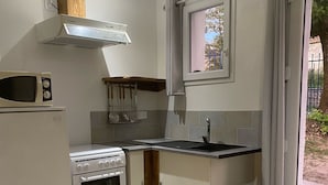 Eine kleine Küche mit Einbauofen, Mikrowelle und einem Fenster mit Vorhängen.