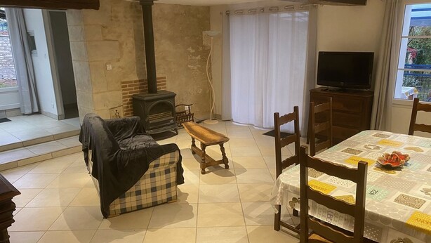 Ein gemütliches Wohnzimmer mit Kamin, Fernseher und Essbereich mit Tisch und Stühlen.