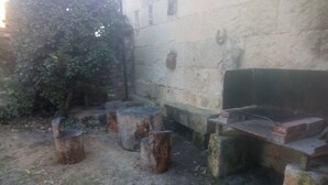 Ein rustikaler Sitzbereich im Freien mit einer Steinsitzbank und Holzschemeln.