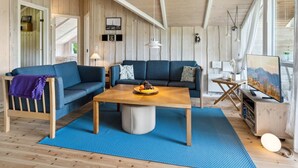 Un salon chaleureux avec un canapé bleu, une table basse en bois et une grande fenêtre.