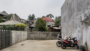 Une cour en béton où est garée une moto appuyée contre un mur, le tout entouré d’immeubles d’habitation.