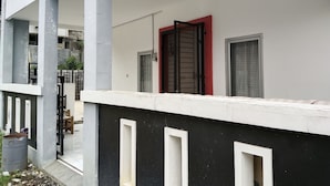 Un immeuble résidentiel doté d’un balcon, d’une porte rouge et d’une fenêtre ornée d’une grille métallique.