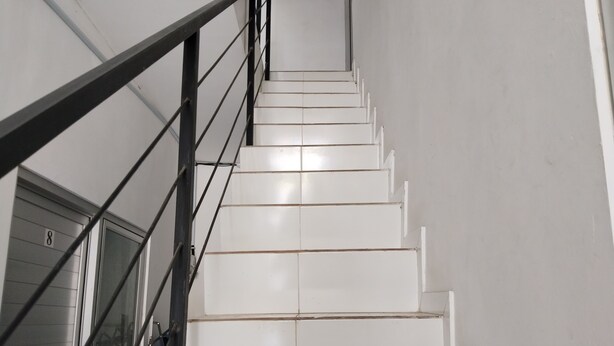 Un escalier avec des marches blanches et une rampe en métal noir.