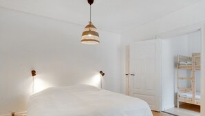 Quarto com cama, luminária pendente e porta de madeira.