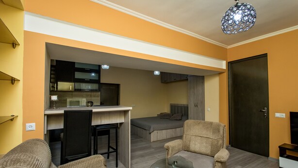 A compact living space with a kitchenette, a sofa, a dining table, and a bed. - HB apartments Opera II (Tbilisi)