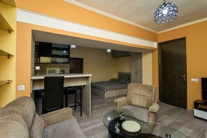 A compact living space with a kitchenette, a sofa, a dining table, and a bed. - HB apartments Opera II (Tbilisi)
