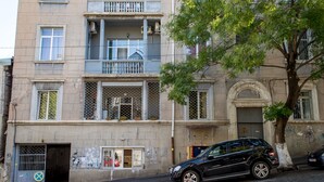A multi-story building with balconies, a tree in front, and a parked car. - HB apartments Opera II (Tbilisi)