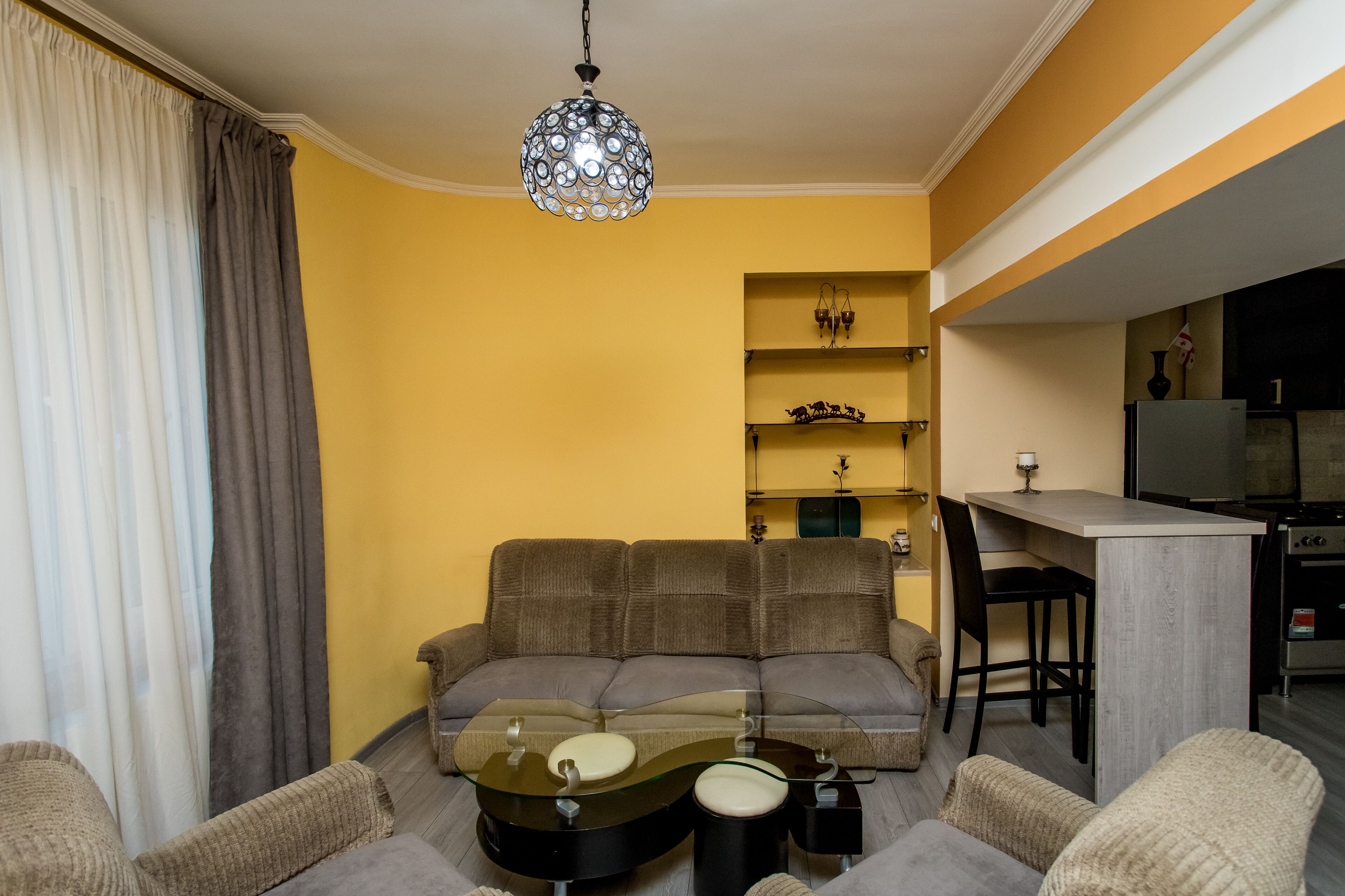 Una sala de estar con sofá, mesa de centro y una zona de cocina con barra.