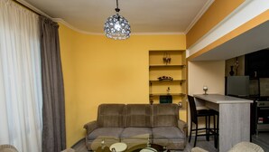 A living room with a sofa, coffee table, and a kitchen area with a bar. - HB apartments Opera II (Tbilisi)