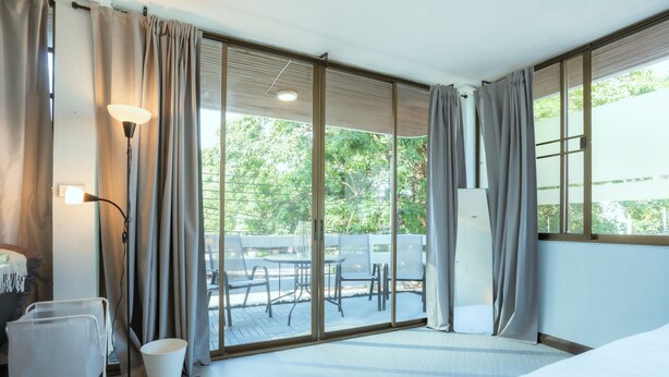 Ein Hotelzimmer mit Bett, Schreibtisch, Lampe und Blick auf die Terrasse.
