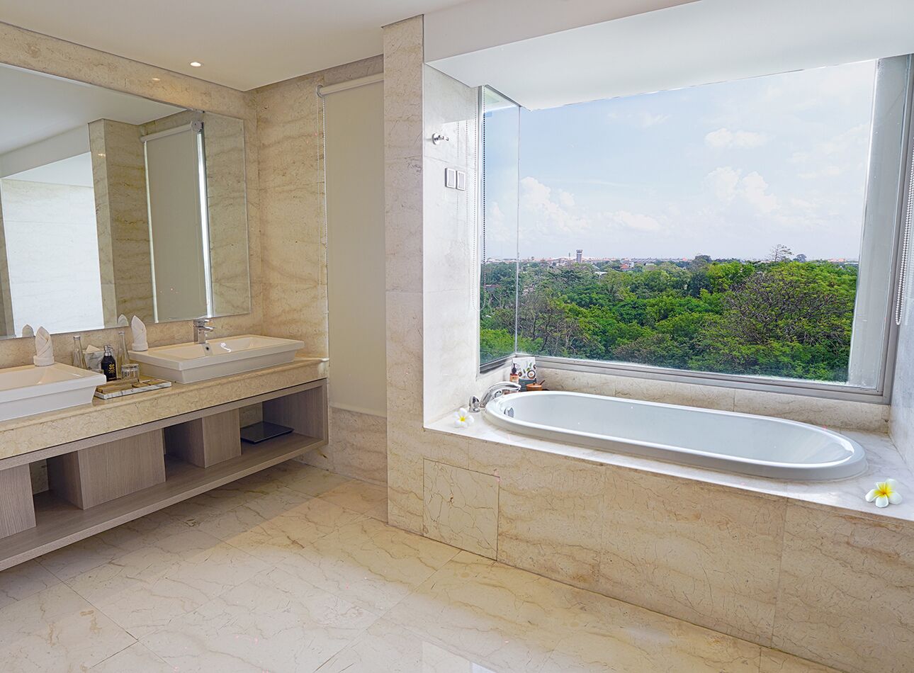 Un baño moderno con una bañera grande y un ventanal que ofrece vistas a zonas verdes.