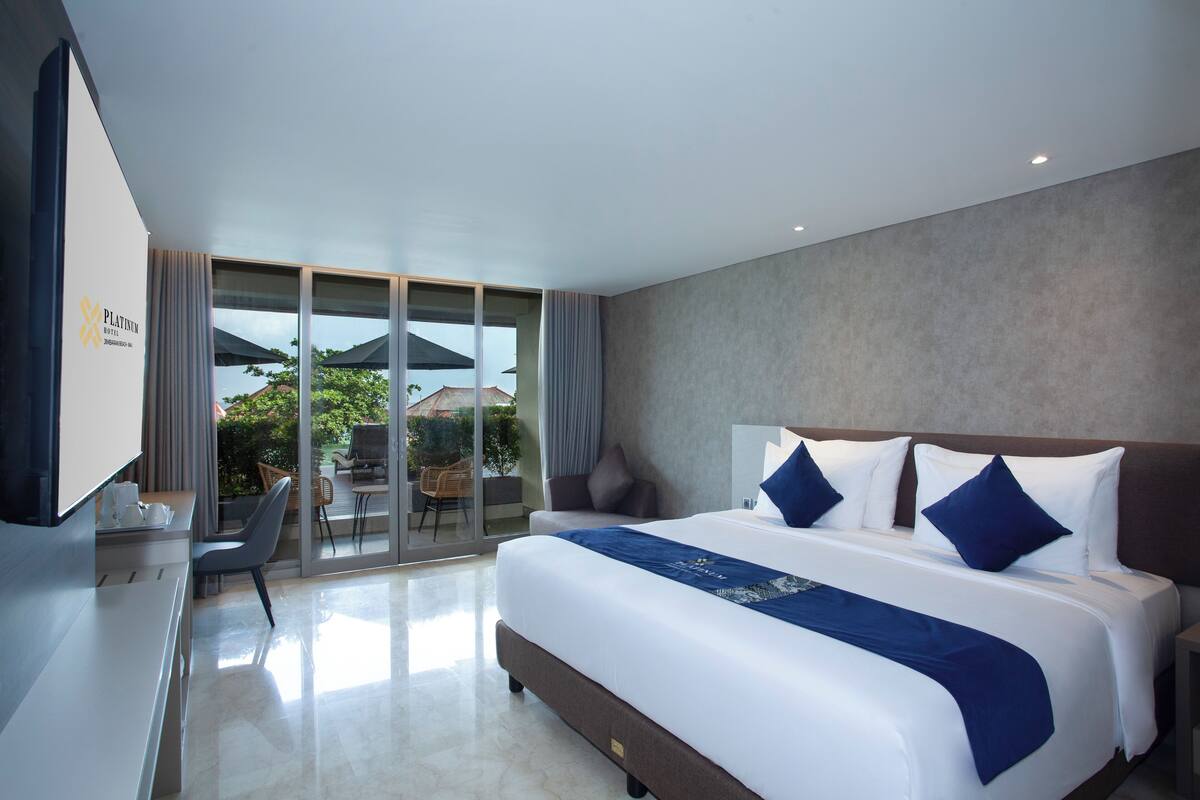 A modern hotel room with a large bed, a desk, and a television.