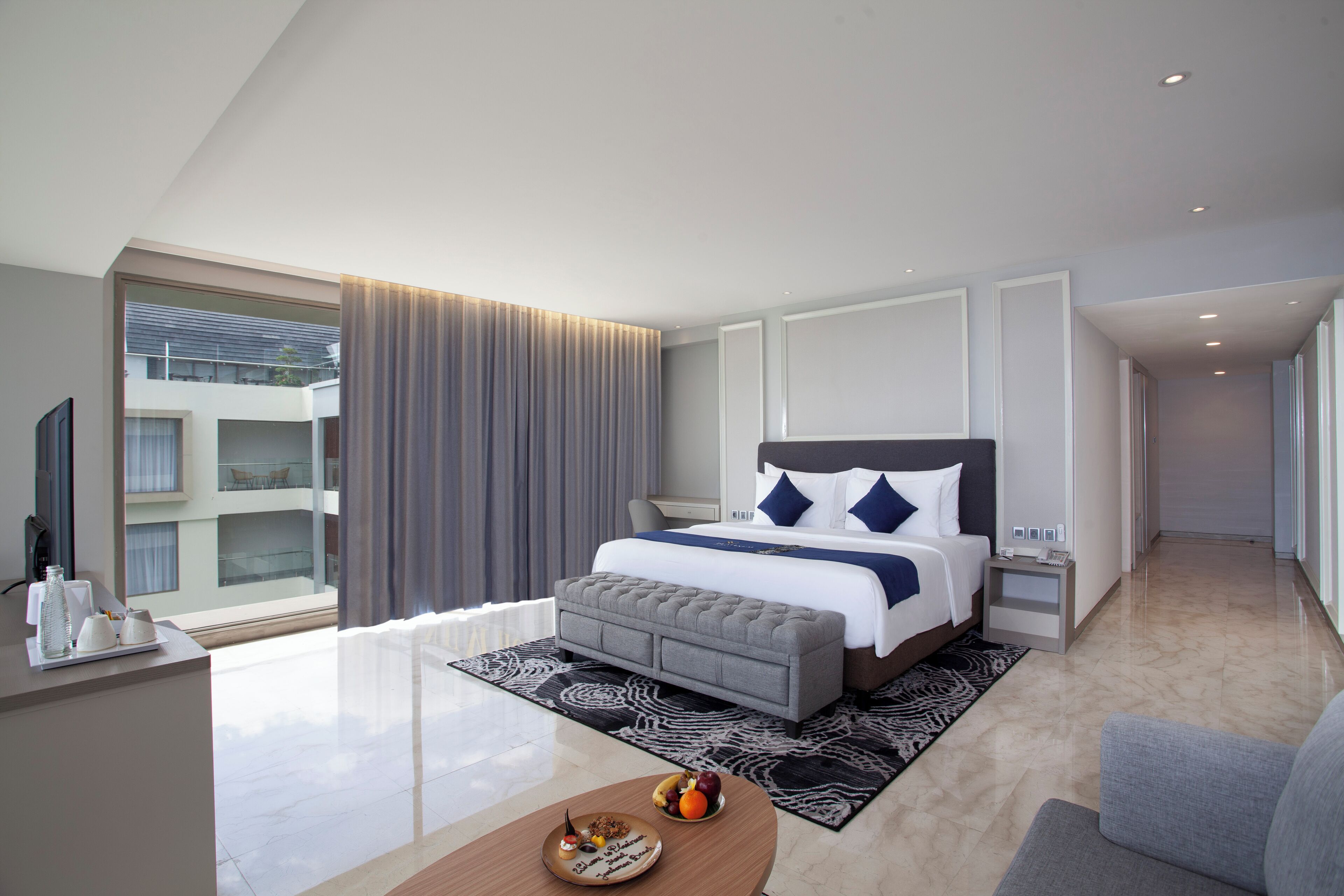 Een moderne hotelkamer met een groot bed, nachtkastje, bureau en uitzicht op de buitenkant van het gebouw.