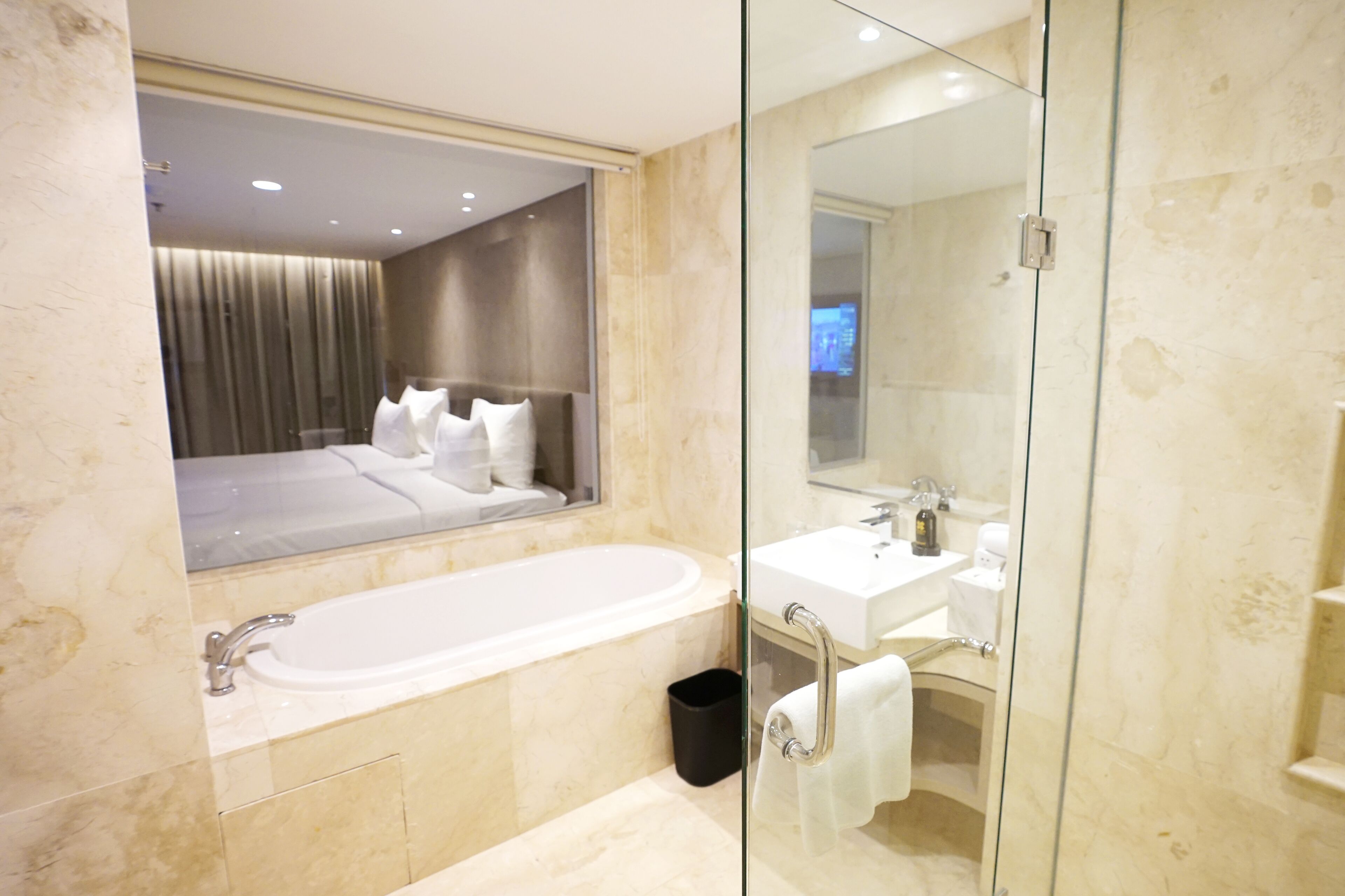 Une salle de bain moderne avec une grande baignoire, une douche à l’italienne en verre, un meuble-lavabo et un miroir.