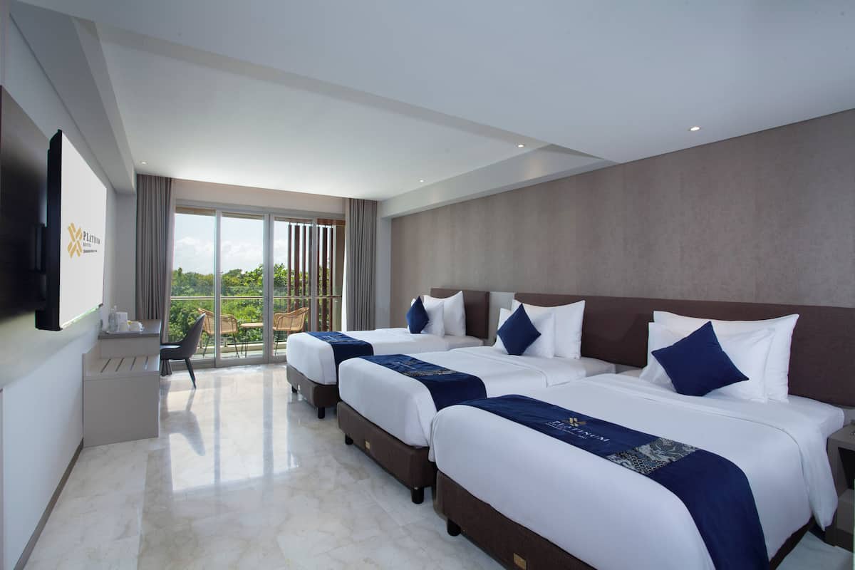 A hotel room with three beds, a desk, and a TV.