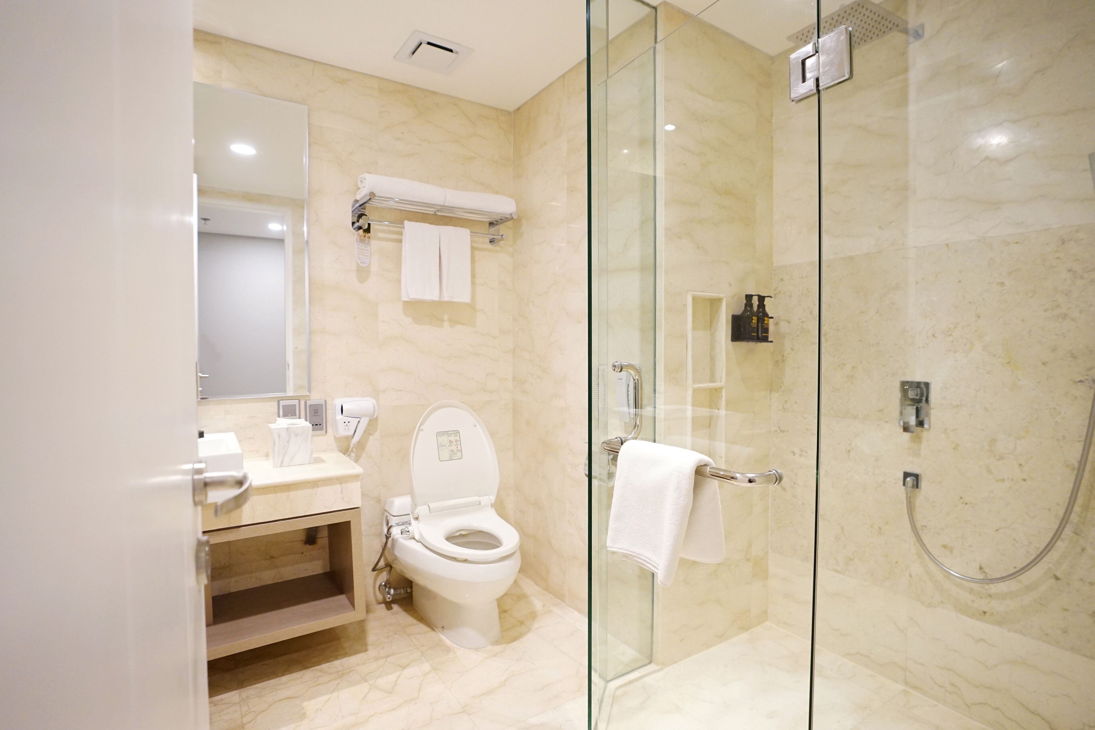 Un baño moderno con ducha de vidrio, inodoro y tocador con espejo.