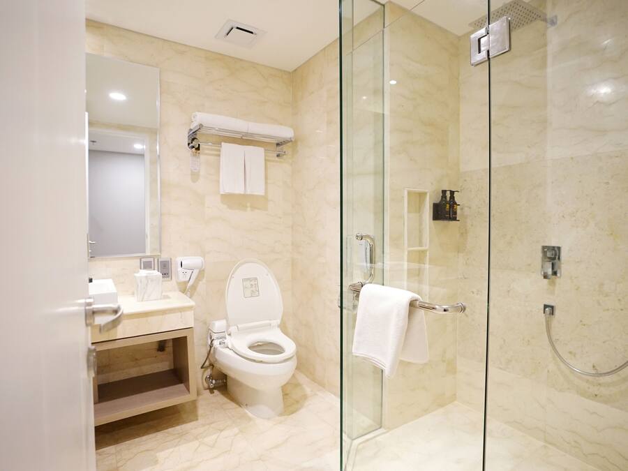 Un baño moderno con ducha de vidrio, inodoro y tocador con espejo.