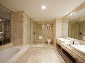 A modern bathroom with a glass-enclosed shower, a freestanding bathtub, and a vanity with two sinks and a large mirror.