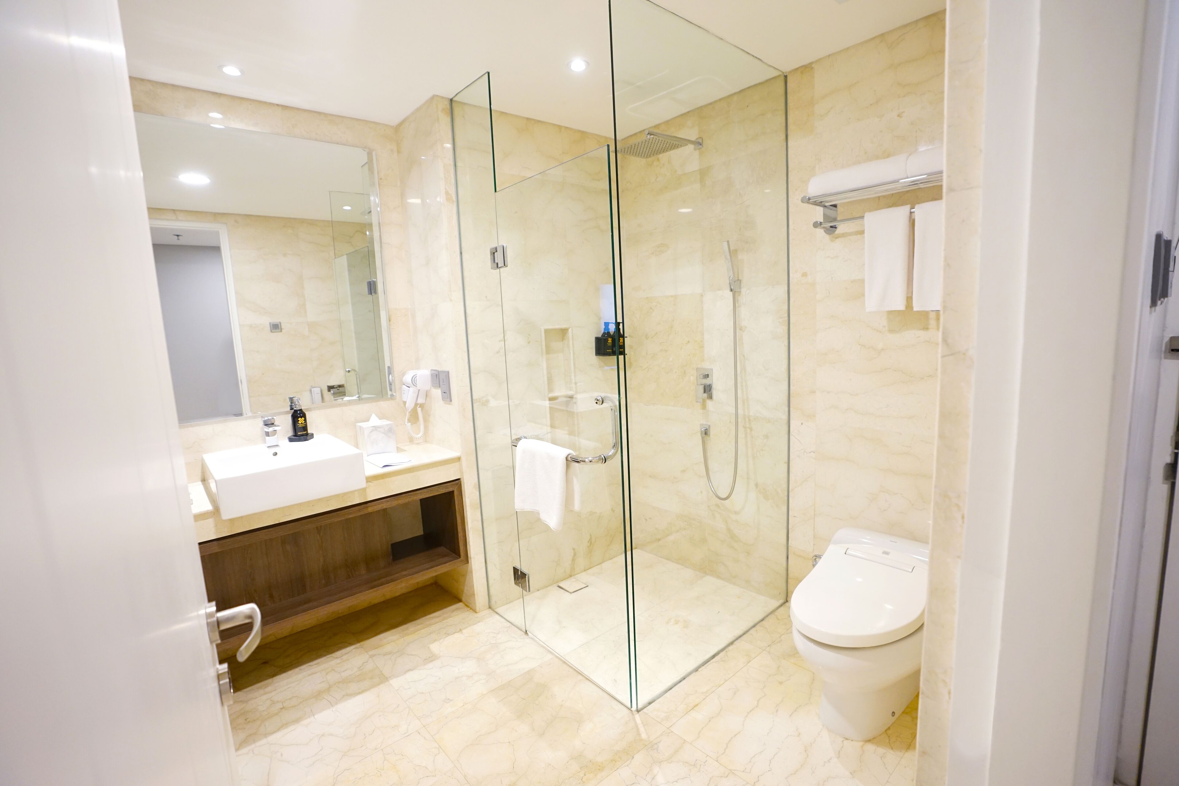 A modern bathroom with a glass-enclosed shower, a white sink, and a toilet.