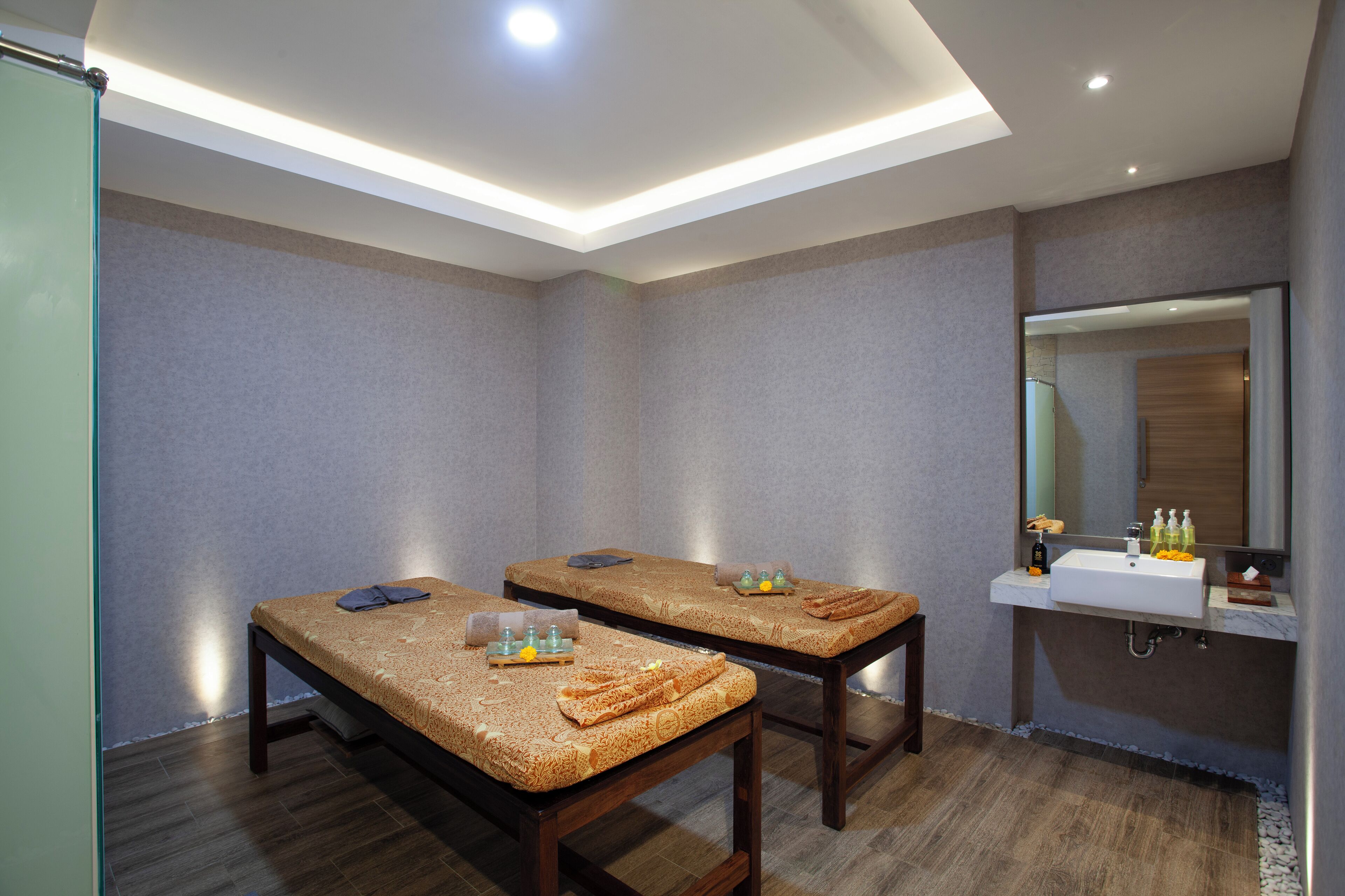 Une salle de spa équipée de deux tables de massage, d’un lavabo et d’un miroir.