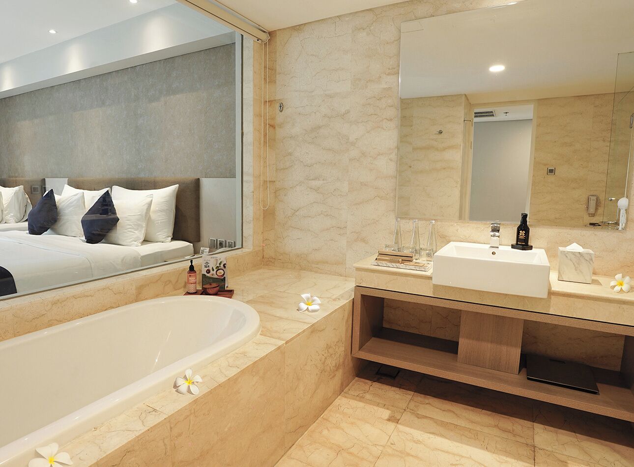 Un baño moderno con una bañera grande, un tocador con espejo y una cama con almohadas.