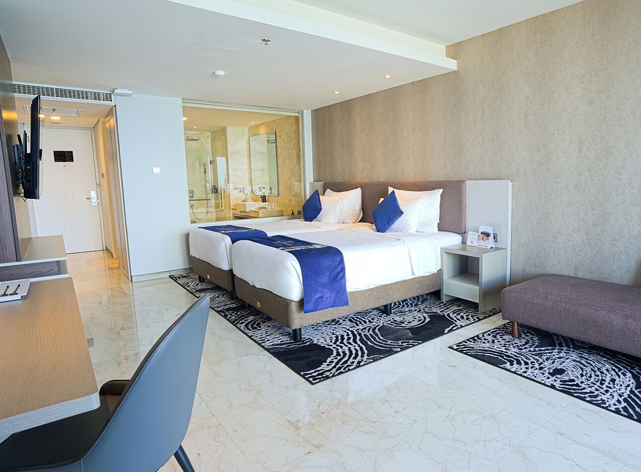 A modern hotel room with a large bed, a desk, and a seating area.