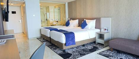 A modern hotel room with a large bed, a desk, and a seating area.