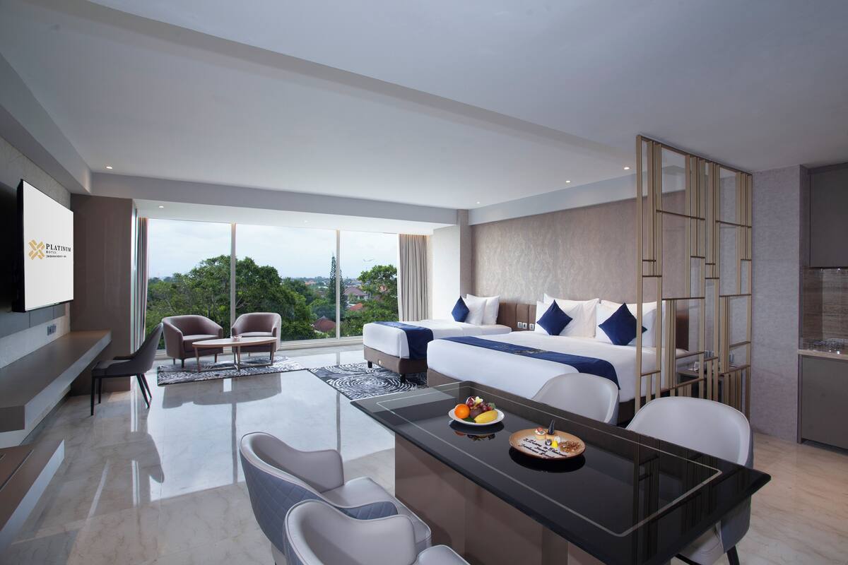 A modern hotel room with a large bed, a dining table, and a TV mounted on the wall.