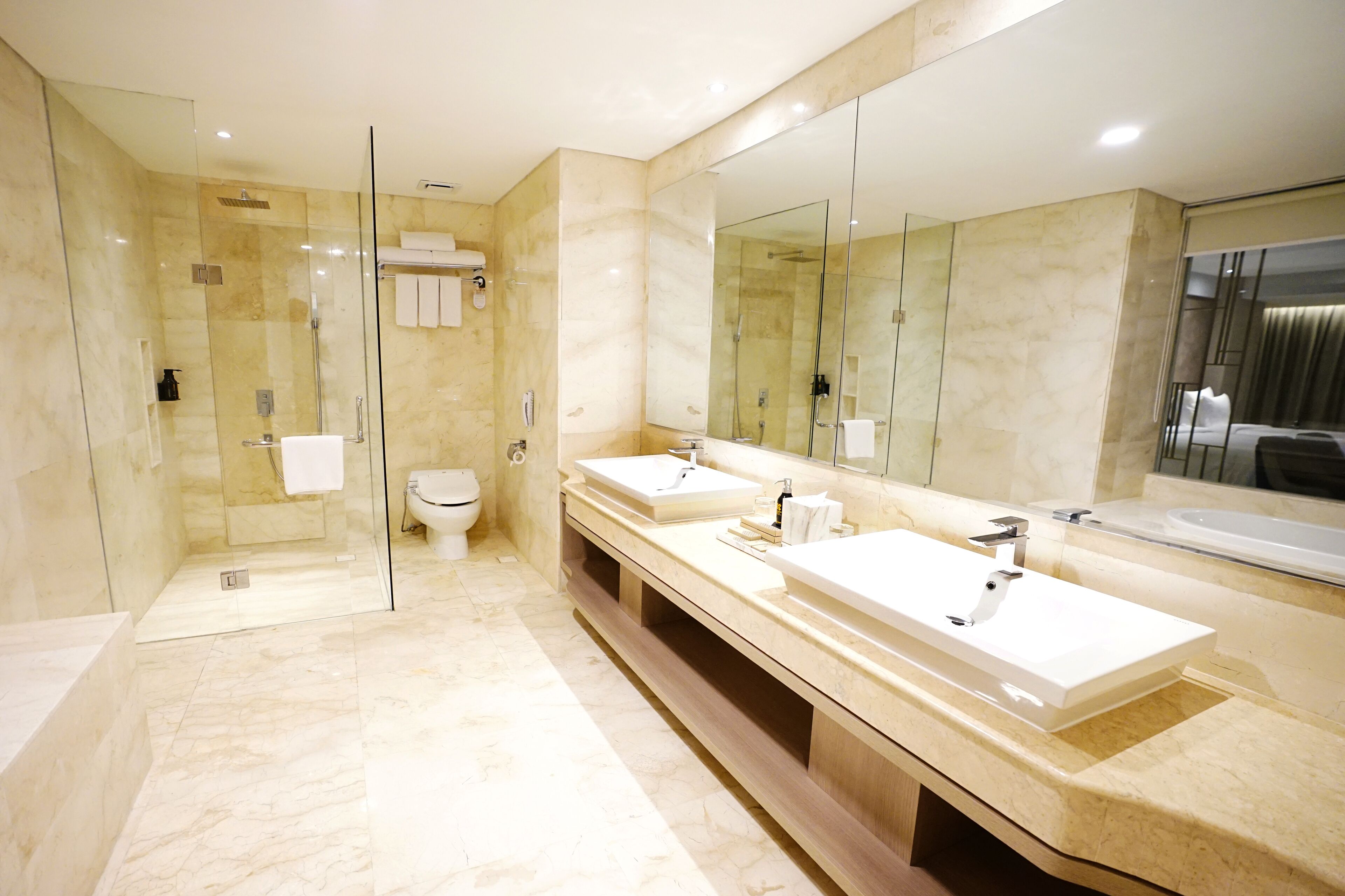 Un bagno moderno con doccia vetrata, due lavabi e un grande specchio.
