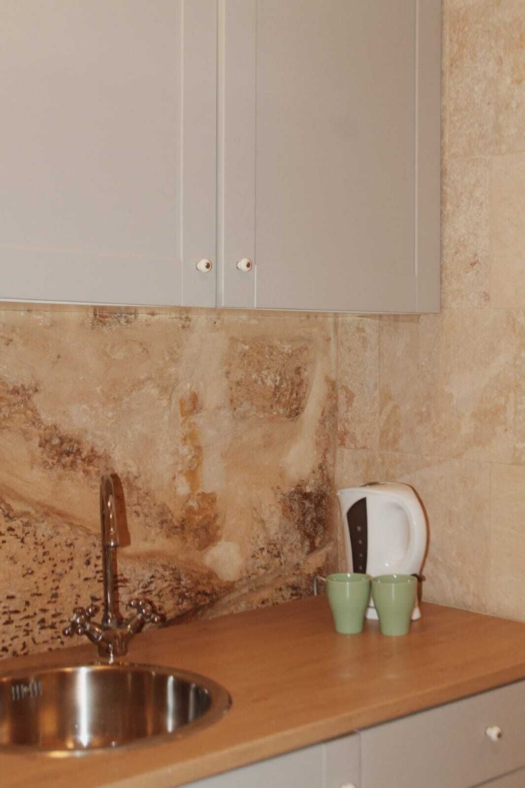 Una cocina con un lavamanos de acero inoxidable, un grifo y una tostadora sobre la encimera.