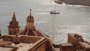 A coastal cityscape with historic buildings and a marina. - Barakka Garden Studio  (Valletta)