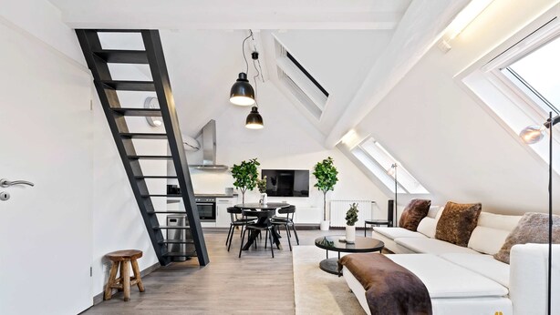 A modern loft apartment with a dining area, kitchen, and living space, featuring a skylight, wooden flooring, and a white sofa. - Modern Loft with Washer, TV & Near Attractions (Ville-Haute)