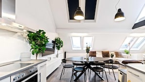 A modern kitchen with a central island, black chairs, and a dining table. - Modern Loft with Washer, TV & Near Attractions (Ville-Haute)