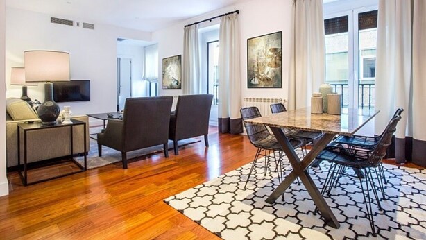 Une chambre d’hôtel moderne dotée d’un coin repas, d’un canapé, d’une télévision et d’œuvres d’art accrochées aux murs.